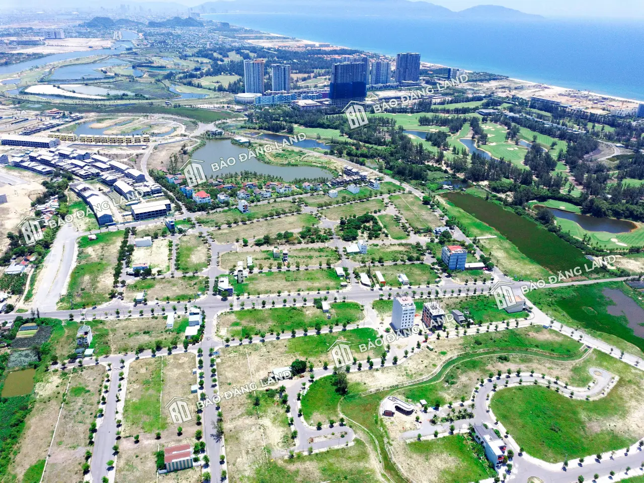 Flycam Sentosa Riverside nhìn về sân golf và dãy cao tầng ven biển, phía trước là các lô đã xây nhà